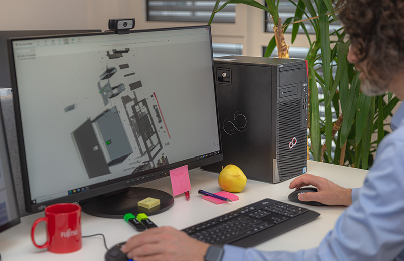 Stacja robocza Fujitsu w czarnej obudowie tower przy biurku, inżynier pracuje w CAD na monitorze