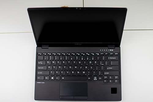 Czarny laptop Fujitsu widziany z góry, z klawiaturą, touchpadem i czytnikiem linii papilarnych