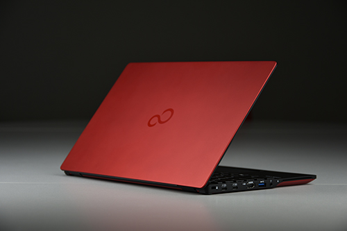Czerwony laptop Fujitsu widziany od tyłu, z logo na pokrywie matrycy i portami z boku.